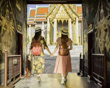 young tourist women walking through the palace temple in Bangkok of Thailand, Emerald Buddha Temple, Wat Phra Kaew, Bangkok Royal Palace popular tourist placeの写真素材