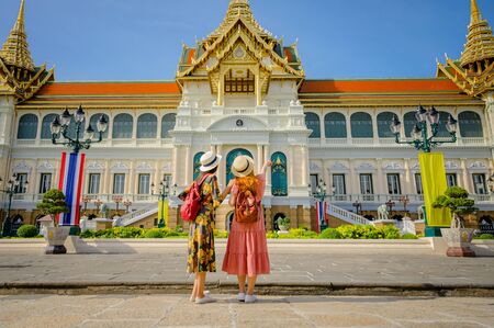 young tourist women enjoy trip walking to the palace temple in Bangkok of Thailand, Emerald Buddha Temple, Wat Phra Kaew, Bangkok Royal Palace popular tourist placeの写真素材