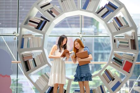 young asian student enjoy reading book together in library of Universityの写真素材