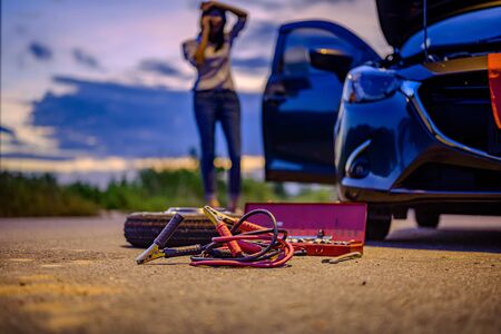 Jumper electric cable and belonging tools prepare by woman driver, need help and assistant at dark of the night, scary and worry alone in the dark, car engine failure or tire need replacementの写真素材