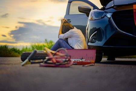 Woman upset waiting for help and assistant at dark of the night, scary and worry alone in the dark, car engine failure or tire need replacementの写真素材