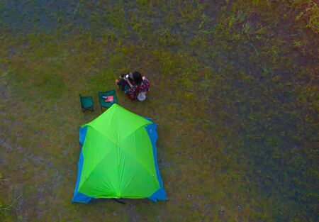 aerial top view of woman tourist stay with tent at the edge of the Lake, prepare overnight staying in lakeの写真素材