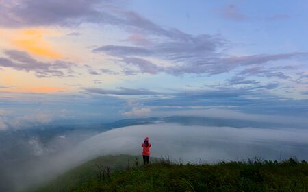 traveller woman enjoy taking photo of the mist flowing in between hills on the peak of mountain