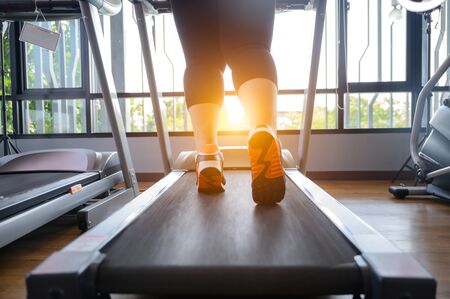 leg of fat woman being run or jog on belt of treadmill machine