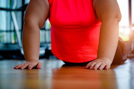 hand and arms of fat plump woman try to lift up body weight in gymnasium