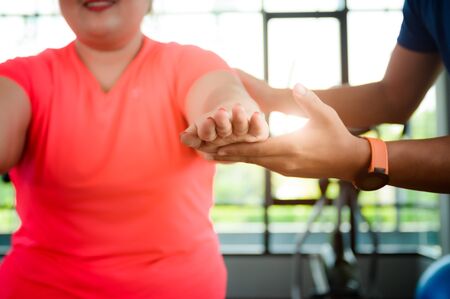 hand of personal trainer or coach touching support to hand of fat plump woman, assist and help in exercise actionの写真素材