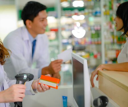 hand of woman pharmacist holding box or case of medicine container, estimation cost of the pills in charge, with customer and consultantの写真素材