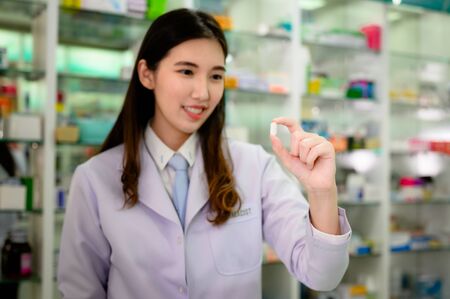 tablet pill in fingers hand of woman pharmacist holding to review for detail of prescriptionの写真素材