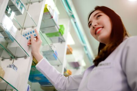 hand of woman pharmaist holding bundle of pills medicine in drug store, selling medicine in phamacy by official phamacistの写真素材