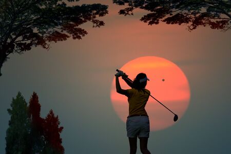 silhouette of woman golf player in action at the end of downswing hit a golf ball to destination in the fairway, best concentrate to destination of life CONCEPTの写真素材