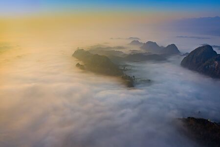 Top aerial view of the scenery landscape of mist and foggy flowing in between the mountains hills...