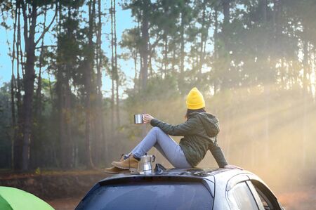 Woman traveller enjoy coffee time on her owns roof of the car with scenery view of the sunrise...