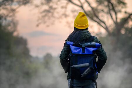 woman trekking alone on the lake of forest mountain with hot spring water flowing the lake in the morning, cheerfully on the move freshly morningの写真素材