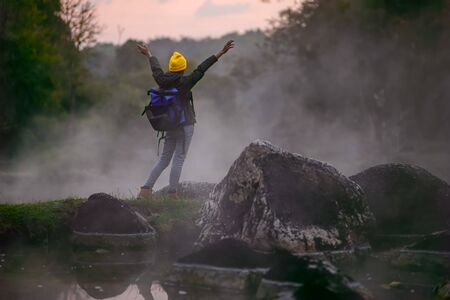 woman trekking alone on the lake of forest mountain with hot spring water flowing the lake in the...
