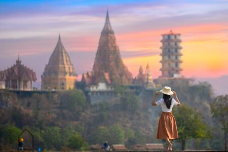 woman farmer walks on the field of rice, taking motion feel free with buddhist temple in background, morning walking to the temple to joint buddha monk ceremony, Thai and asian culture 
の写真素材