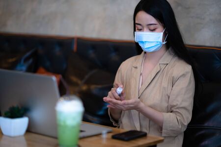 woman wearing protection mask with alcohol always cleaning hand against infection of covid-19, in worry and serious motion of woman working outdoors in situation of virus infectの写真素材