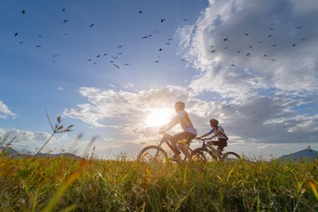 family couple lover enjoy the life of riding biking on the fresh field meadow grass, cheerfully life holding hand together on outdoors activityの写真素材