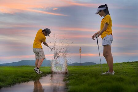 splash of the water in channel raceway of the golf course, hit golf ball away to destination on the green by golf player, along with golf-mate or competitor in an exciting beside in backgroundの写真素材