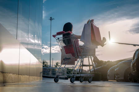 cheerfully of woman sitting in shopping cart, happy woman sits in shopping cat at department storeの写真素材