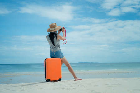 Woman tourist traveller standing on the sea beach ready going to the trip journey to explore the Worldの写真素材