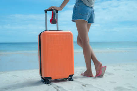 Woman tourist traveller standing on the sea beach ready going to the trip journey to explore the Worldの写真素材