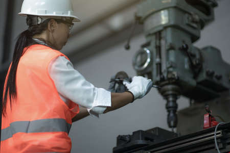 Woman engineering technician or inspection quality control working on machinery drilling metal with...