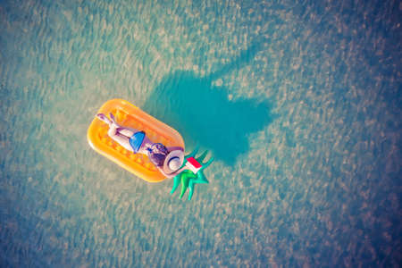 woman in bikini enjoy swimming on inflatable tube at the sea island, summertime enjoyment in the sea alone, weekend and vacation enjoyment in the sea summertimeの写真素材