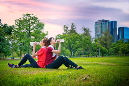 women in action of thirsty water after excercise jogging in city publick park, enjoy happylifes together excercise for healthy slim lifeの写真素材