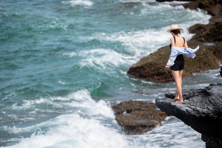 Women traveler enjoy the trip by standing to the natural cliff of the sea, summer moment on trip travelingの写真素材