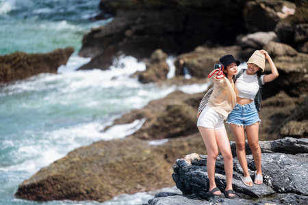 Women traveler enjoy the trip of hiking to the natural cliff in the sea, summer moment on trip...