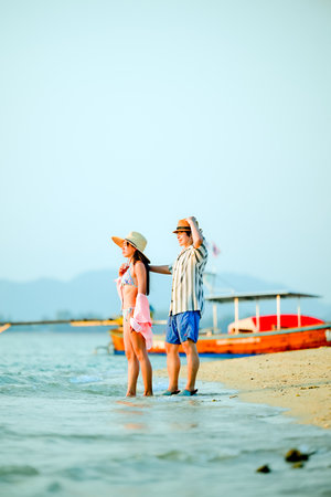 Couple traveler enjoy trip traveling together at the edge of the sea beach, summertime traveling together enjoymentの写真素材
