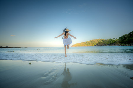 Woman tourist in dress play around on the sand of the sea, enjoy moment of the woman at the edge of the sea beach in summer courseの写真素材