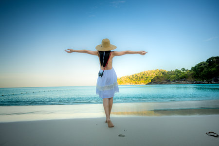 Woman tourist in dress play around on the sand of the sea, enjoy moment of the woman at the edge of the sea beach in summer courseの写真素材