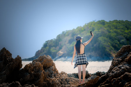 Woman tourist in motion of taking photo of the summer nature, enjoy moment of the woman at the edge of the sea stone  in summertimeの写真素材