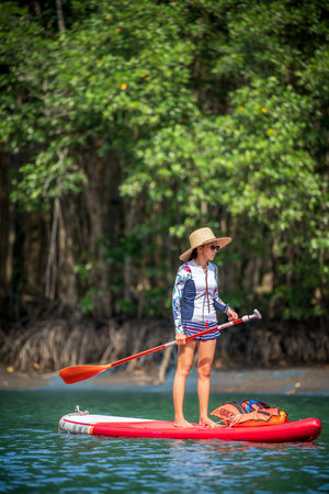 Women enjoy standup paddle board in the natural lake river of rainforestの写真素材