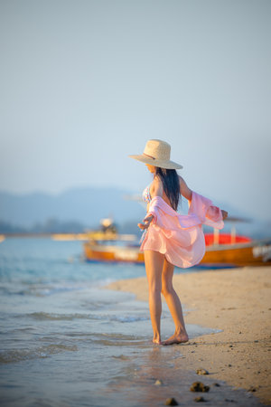 Woman standing relax posting at the edge of the sea beach, summertime travelingの写真素材