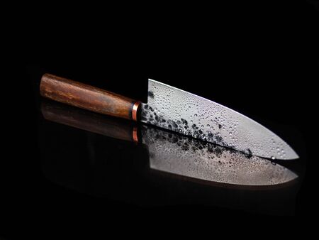 handmade knife for the chef, wooden handle, steel blade, on a black mirror background, drops on the...