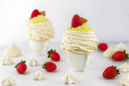 Pavlov's (pavlova) cakes with strawberries, on a white cup, around strawberries and meringues, white...