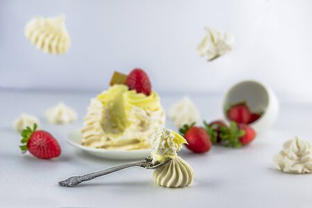 Pavlov's (pavlova) cake with strawberries, on a white saucer, vintage spoon, strawberries falling...