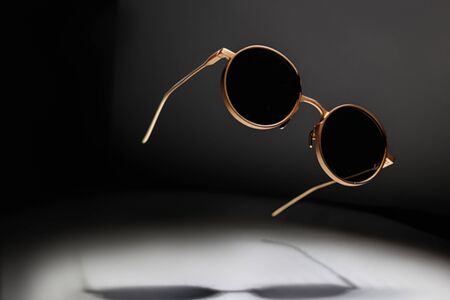 sunglasses levitate on a dark background, play of light