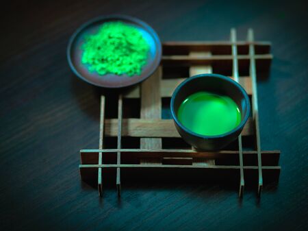 matcha tea in a clay cup, next to tea powder, dark backgroundの写真素材