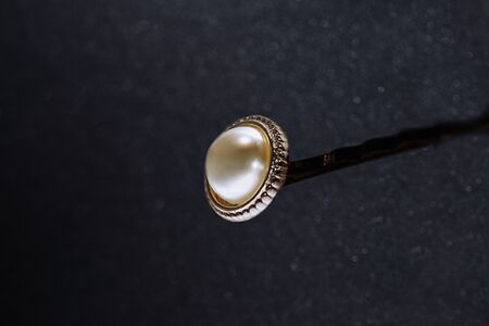 golden hair clip with pearls on a dark background, low key, play of lightの写真素材