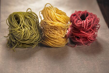 multi-colored pasta nests, on baking paper, red, yellow and green colorsの写真素材