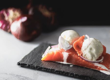 ice cream with sweet onions on a fillet of red fish, stone stand, on a background of lemon, red onionの写真素材