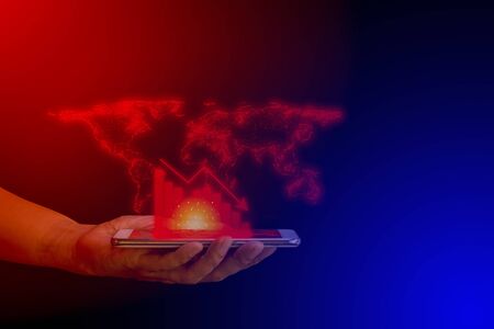 Hand hold smartphone and red graph drop arrow down with world map on blue technology background. and copy space. Money losing. Stock crisis and finance concept.の写真素材