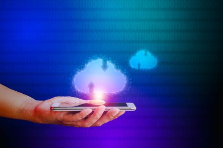 Hand holding smartphone with cloud icon on blue and green binary code background. Communication of business and financial. Cloud data storage concept.の写真素材