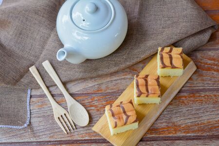 Cube cut of butter cake on wooden tray and table for served in party. Delicious dessert eat with tea and coffee in morning.の写真素材