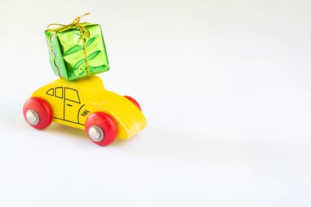 Green gift box with golden ribbon on yellow wooden car on white background with copy space. Christmas and new year concept.の写真素材