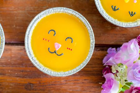 Top view minimal orange cake with butter cream smile in foil cup on wooden table. Delicious bakery...
