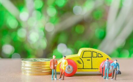 Group of business man Miniature people, small model human figure sell or buy  wooden yellow car and stack of gloden coins with green bokeh background. Copy space for your text. Business and financial concept.の写真素材